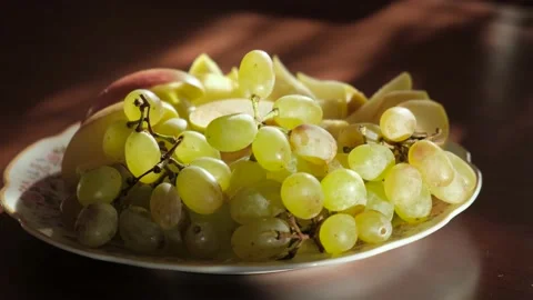 Man eating fresh grapes from a plate of fruit, close-up Video stock 165166313
