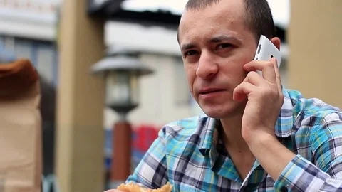 Man Eating A Hamburger And Talking On The Phone Stock Footage 71152431