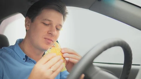 A man is eating a hamburger in a car. Stock Footage 81816580