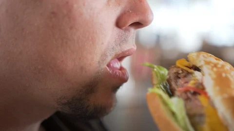 Man eating hamburger fast food, close-up Stock Footage