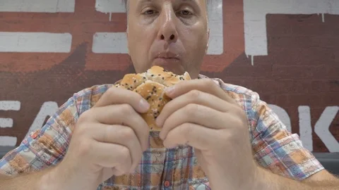 The man is eating a hamburger. 스톡 동영상 92635620
