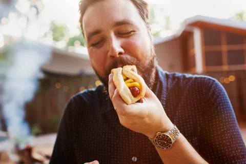 Man eating hot dog at yard Stock Photos