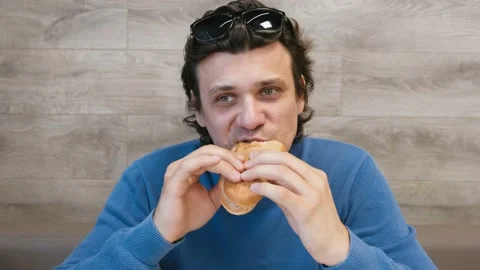 Man is eating a hotdog in cafe. Stock Footage
