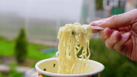Man eating instant egg noodles outdoors Stock Footage 346122087