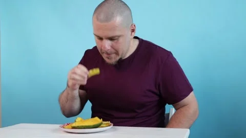 Man Eating Mango Slice on Blue Background, exotic fruit as a symbol of natu.. Stock Footage 305980908