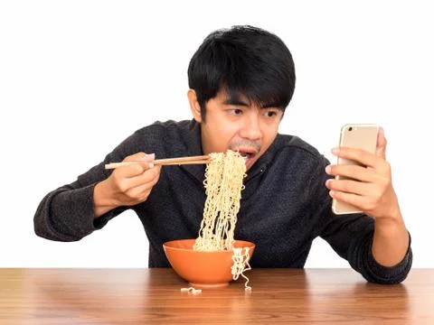 Man eating noodle and using smartphone isolate Stock Photos