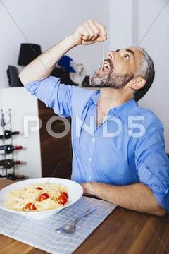 Man eating pasta in his kitchen Stock Photos