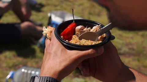 Man eating pilaf from a plastic plate in the mountains, gaining strength Stock Footage 158664000