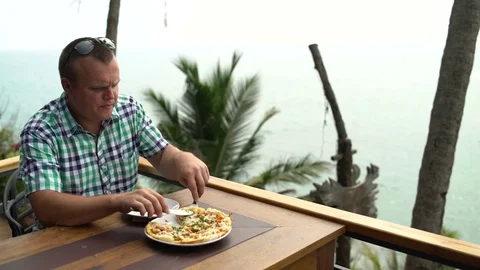 A man is eating pizza at a cafe Stock Footage 74892504