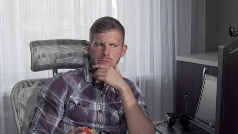 Man eating pizza while working on a project on his computer Stock Photos