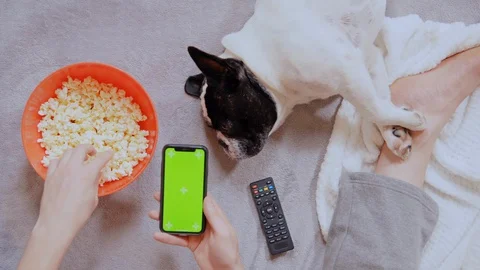 Man eating popcorn using mobile indoors Stock Footage 127844102