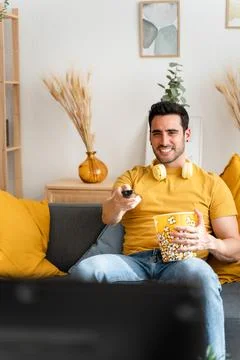 Man eating popcorn while watching tv. Stock Photos