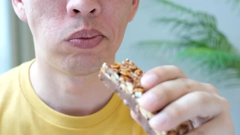 Man eating protein bar on a gray background close-up. Stock Footage 181951758