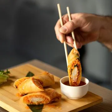 Man Eating Rolls with Sauce Using Chinese Chopsticks. Delicious oriental dish Stock Photos