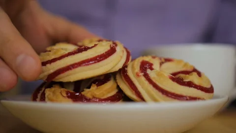 A man is eating a round cookie with jam. Hands taking homemade sweets from th Stock Footage 95653059