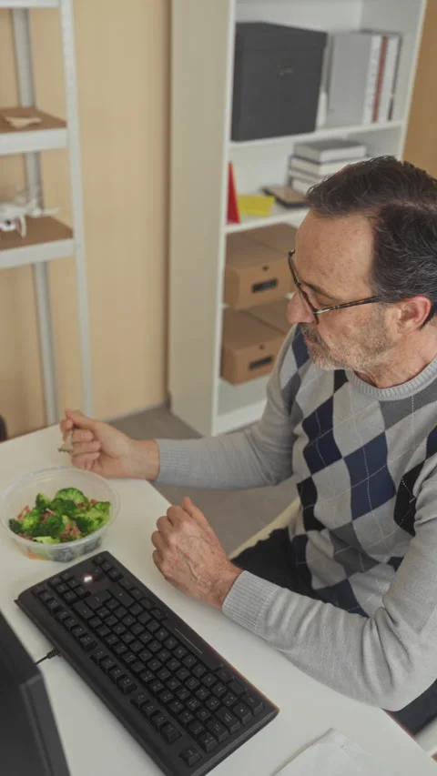 Man eating salad with fork at computer desk in office building, hand steady.. Stock Footage 337442151