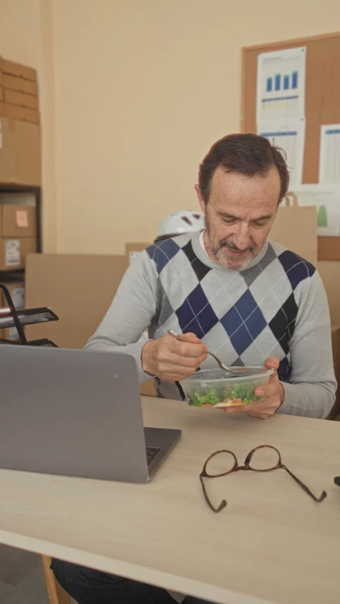 Man eating salad with fork at desk in building office, holding plastic cont.. Stock Footage 337442373