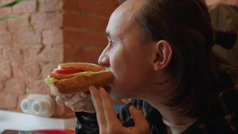 Man Eating Sandwich Close Up With Brick Wall Plant Background showing tomato Stock Footage 344873469