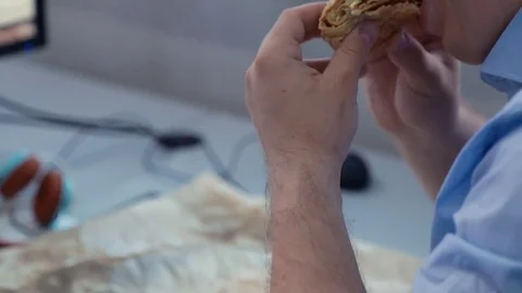 Man eating a sandwich in the workplace Stock Footage 76400599