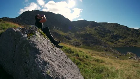 A man eating a snack in the mountains while hiking 스톡 동영상 163027286