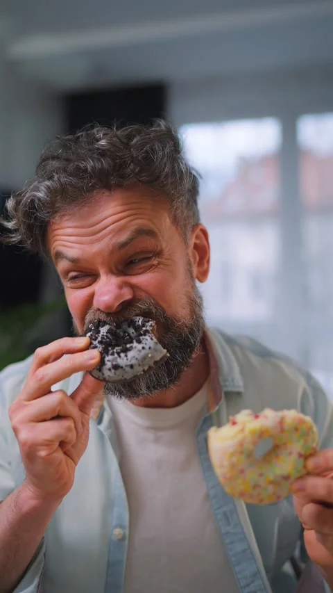 A man eating two donuts and looking around to make sure no one is watching Stock-Footage 342954963