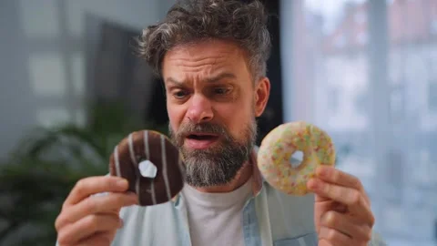 A man eating two donuts simultaneously with delight. Sugar addiction. Slow Stock Footage 346728593