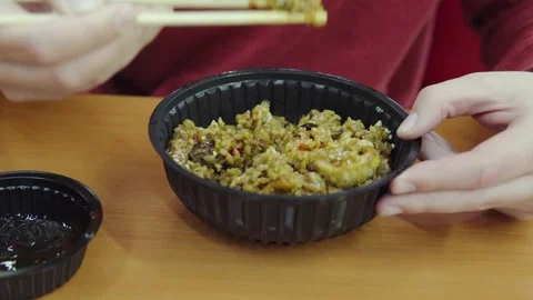 A man eats asian food with disposable wooden chopsticks from plastic plate Stock Footage 161820201