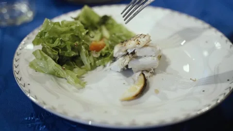 A man eats a baked piece of sea bass with lemon juice and herbs. Vidéo 254340016
