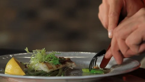 A man eats blanched asparagus and grilled fillet of pike perch, served with Stock Footage 116890634