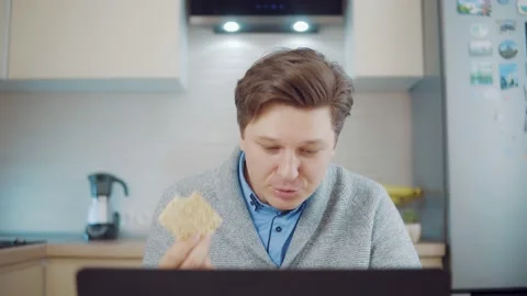 A man eats bread while working at a laptop Stock Footage 148816240