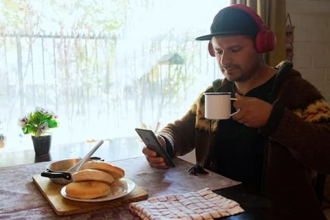 Man eats breakfast while checking his cell phoneman eats breakfast while ch.. Stock Photos