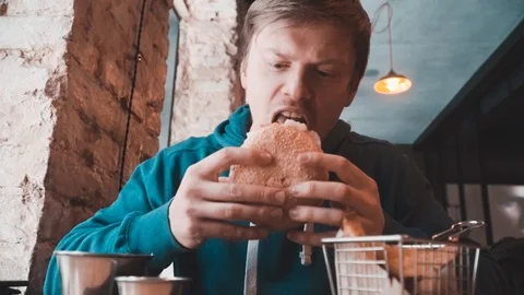 A man eats, burgers at a table in a cafe Stock Footage 87285697