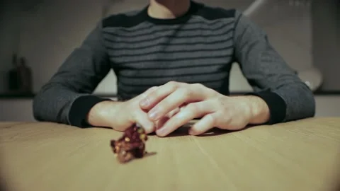 A man eats a candy and twirls a candy wrapper in his hands, close-up Stock Footage 166258910