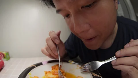 Man Eats Chicken with Fork and Spoon at Dining Table in Bright Indoor Setting Stock Footage 335433171