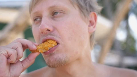 The man eats chicken wings an outdoor. Fast food Stock Footage 127843260