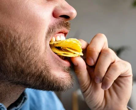 Man eats chips, closeup photo of the eating mouth. Unhealthy eating. Foto stock