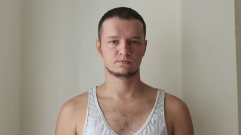 A man eats a cucumber on a white wall background. Stock Footage 119720804