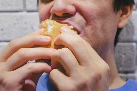 Man eats a delicious hamburger with an appetite in a cafe. Lips close-up. Foto stock
