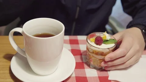 A man eats dessert in a glass of trifle and drinks tea. Food on the first date Stock Footage 161360748