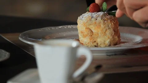 A man eats Dessert Millefeuille, garnished with raspberries and mint on a white Stock Footage 116774882