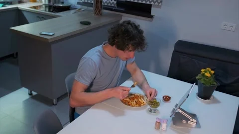 Man eats dinner while watching digital tablet at home Stock Footage 317801155