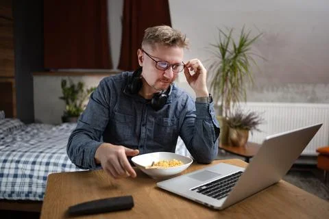 Man Eats Dinner While Working On Laptop At Home Stock Photos