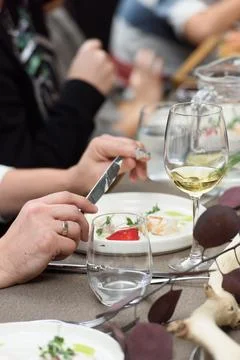 Man eats a dish of fish balls in a creamy sauce served on a table in a Foto stock