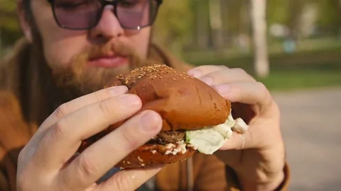 Man eats eating hamburger outdoors. Close-up Vidéo 154208916