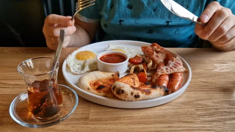 A man eats an English breakfast in a cafe Stock Footage 243712505