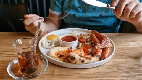 A man eats an English breakfast in a cafe Stock Footage 243713600