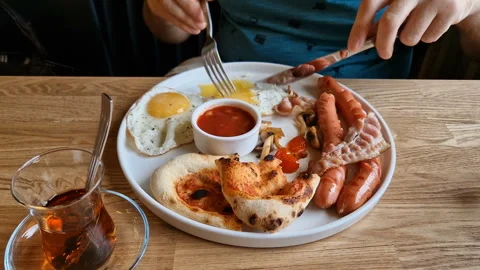 A man eats an English breakfast in a cafe Stock Footage 243803893
