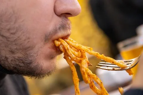 Man eats fat pasta, sucks it with his mouth. concept of obesity, diabetes Foto stock