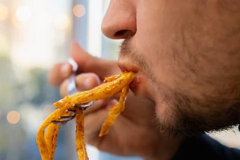 Man eats fat pasta, sucks it with his mouth. concept of obesity, diabetes Stock Photos