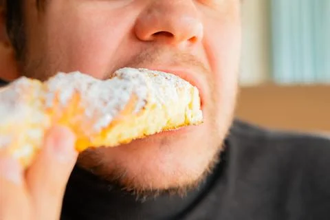 Man eats freshly long curd baked sweet pastry bun in bakery cafe. Tasty sweet Stock Photos